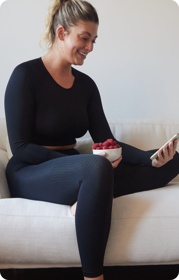 woman looking at phone eating strawberries